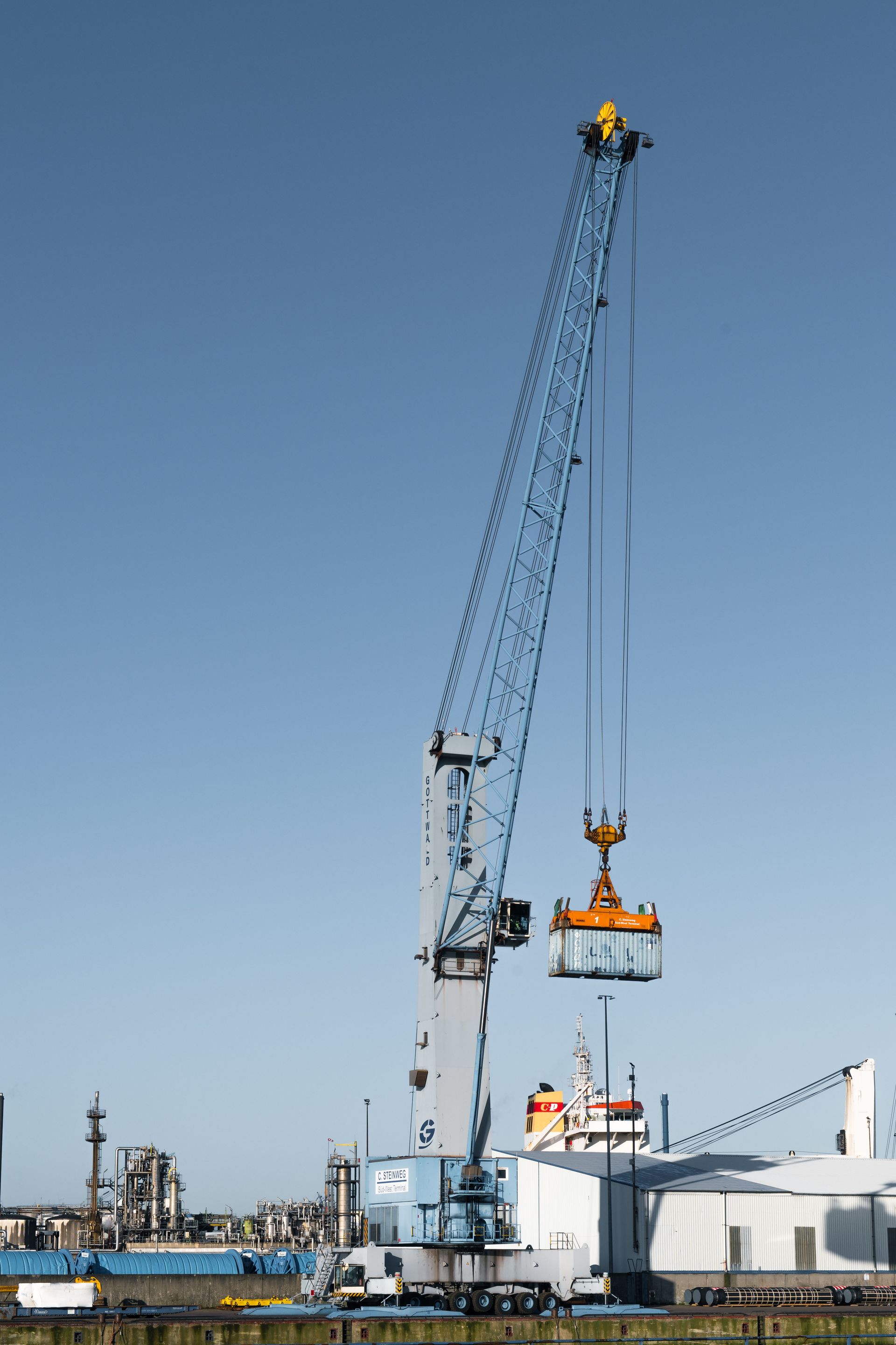 A towering crane operates at Hamburg port, symbolizing global trade and logistics.
